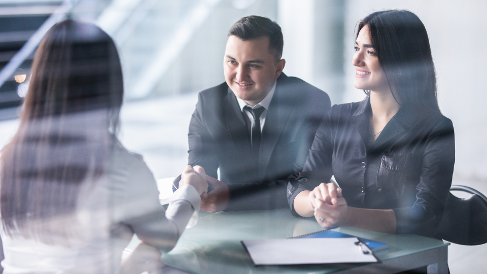 Three people sitting at a desk having a conversation.