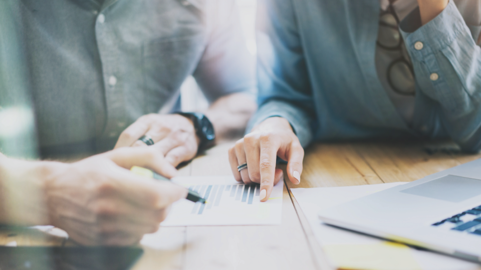 Two people sitting next to each other going through a piece of paper.
